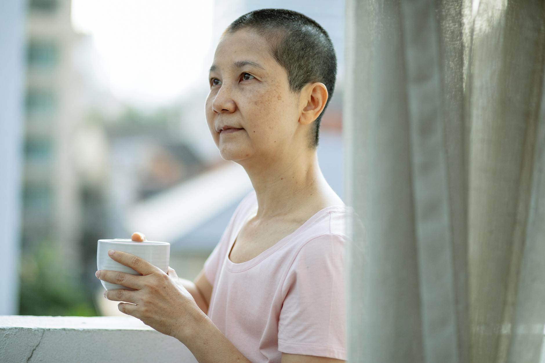 adult pensive ethnic woman drinking coffee on terrace